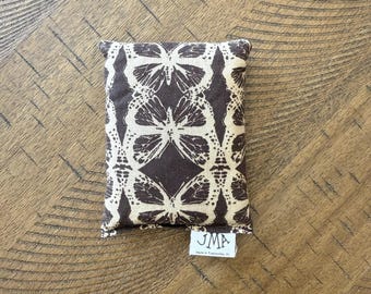 May include: A brown fabric pouch with a white butterfly pattern. The pouch has a small white tag with the text "JMA Made in Tennessee, AL" on it.