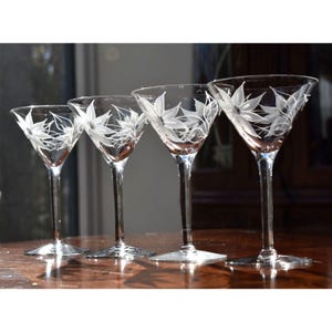 May include: Four clear glass martini glasses with etched floral designs. The glasses are arranged in a row from smallest to largest.