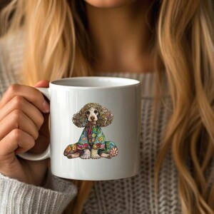 May include: White ceramic mug with a colorful illustration of a dog wearing a floral patterned outfit. The dog has brown fur and is sitting with its legs crossed.