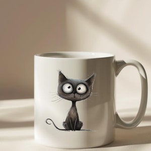 Puede incluir: Taza de cer&aacute;mica blanca con una ilustraci&oacute;n de un gato negro. El gato tiene ojos grandes y una expresi&oacute;n de sorpresa. La taza tiene un asa.