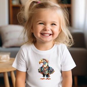 May include: A young girl wearing a white t-shirt with a colorful cartoon bird design. The bird is wearing a hat and glasses.