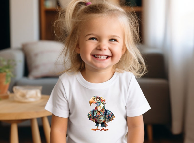 May include: A young girl wearing a white t-shirt with a colorful cartoon bird design. The bird is wearing a hat and glasses.