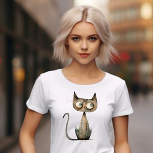 Puede incluir: Camiseta blanca con una ilustraci&oacute;n de dibujos animados de un gato gris con ojos grandes. El gato est&aacute; sentado con la cola enroscada alrededor de sus patas.