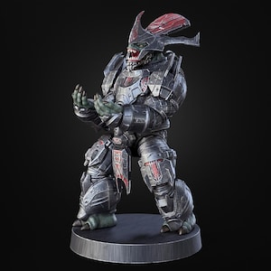 May include: A detailed figurine of a science fiction character in dark armour with red accents. The figure has a green face and hands, and is posed with its hands open. It stands on a circular base.