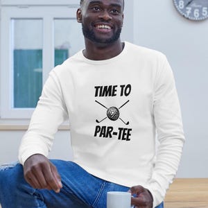 May include: White long-sleeve sweatshirt with black text that reads "Time to Par-Tee" with a golf ball and crossed golf clubs.