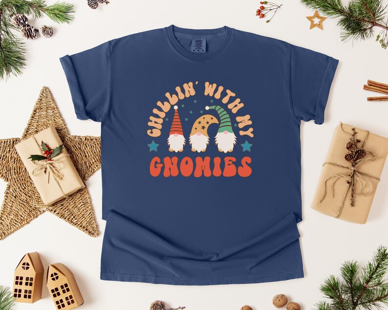 Puede incluir: Camiseta azul marino con el texto "Chillin' with my Gnomies" y un gr&aacute;fico de tres gnomos. Los gnomos tienen barbas blancas y llevan sombreros. La camiseta est&aacute; rodeada de decoraciones navide&ntilde;as.
