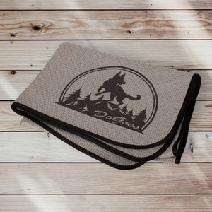 May include: A gray microfiber dog towel with a brown border and a black silhouette of a dog running through a forest with the text "Dog Goes" in a circle.