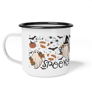 May include: White enamel mug with a black rim. The mug features a spooky Halloween design with ghosts, bats, pumpkins, and leaves. The text "Spooky" is written in black cursive.