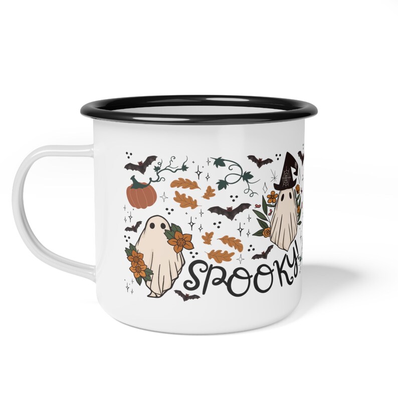 May include: White enamel mug with a black rim. The mug features a spooky Halloween design with ghosts, bats, pumpkins, and leaves. The text "Spooky" is written in black cursive.