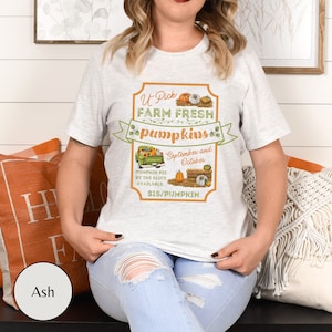 May include: A white t-shirt with a graphic of a vintage truck with pumpkins and the text "U-Pick Farm Fresh Pumpkins September and October $15/Pumpkin".