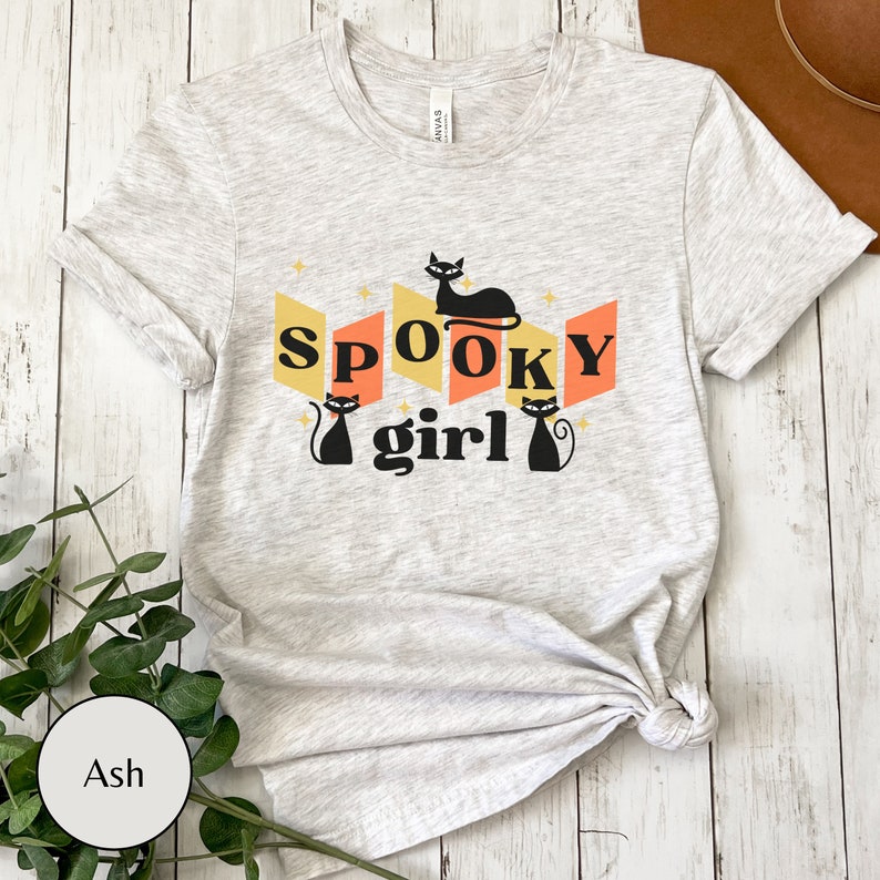 May include: A gray t-shirt with a black cat graphic and the text "Spooky girl" in a retro style.