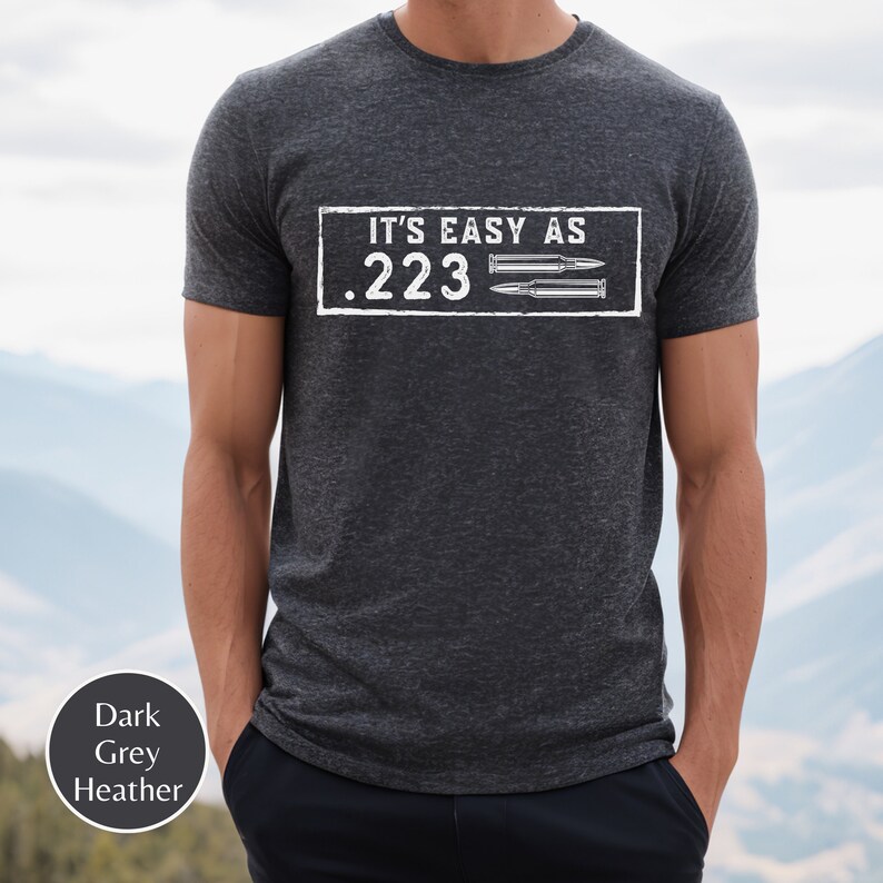 Peut inclure: Un t-shirt en gris chin&eacute; fonc&eacute; avec le texte "IT'S EASY AS .223" et deux douilles de balles imprim&eacute;es sur le devant.