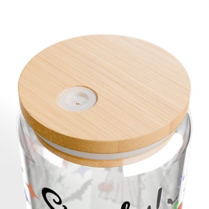 May include: A glass jar with a bamboo lid and a white silicone seal. The jar has a Halloween-themed design with bats, ghosts, and pumpkins. The lid has a small hole in the center.
