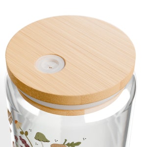 May include: A glass jar with a bamboo lid and a white silicone seal. The jar has a whimsical design featuring mushrooms, leaves, and acorns.