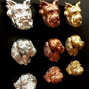 May include: Nine dog head sculptures in silver, gold, and copper finishes. The sculptures are arranged in three rows of three.