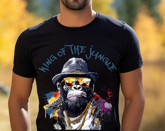 May include: Black t-shirt with a graphic of a gorilla wearing a hat and sunglasses. The gorilla is wearing a gold chain and has a colorful paint splatter background. The text "King of the Jungle" is written in blue above the gorilla.