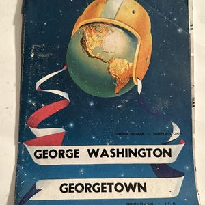 May include: A vintage program for a football game between George Washington and Georgetown. The cover features a globe wearing a football helmet, with a red, white, and blue ribbon. The game was held at Griffith Stadium on November 19, 1949.