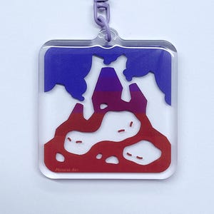 Puede incluir: Un llavero morado con un dije de acrílico transparente que presenta un diseño abstracto rojo y azul. El dije tiene el texto "Noodle An" en la parte inferior.