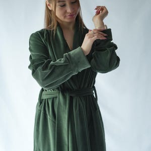 Pu&ograve; includere: Lungo accappatoio in velluto verde scuro con collo a scialle e cintura abbinata. L'accappatoio ha maniche lunghe e una vestibilit&agrave; rilassata. Il tessuto appare morbido e lussuoso. L'accappatoio &egrave; adatto per rilassarsi o come elegante copricapo.