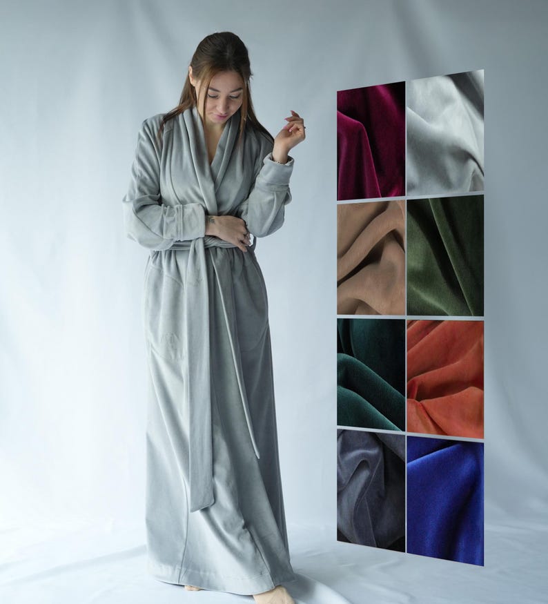 Pu&ograve; includere: Un lungo accappatoio grigio chiaro con cintura abbinata. L'accappatoio &egrave; realizzato in un materiale morbido e ha un collo a scialle. A destra, un'esposizione di campioni di tessuto di velluto in vari colori.