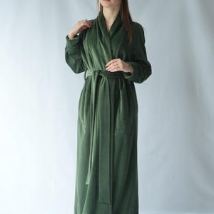 Pu&ograve; includere: Un lungo accappatoio verde oliva con collo a scialle e cintura abbinata. L'accappatoio &egrave; realizzato in un materiale morbido e vellutato e ha tasche. Le maniche sono lunghe e l'accappatoio arriva alle caviglie.