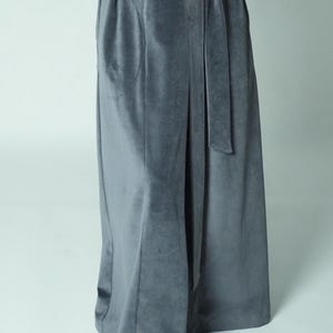 Pu&ograve; includere: Gonna lunga in velluto grigio con cintura abbinata. La gonna ha una vita alta e una leggera forma ad A. Il tessuto appare morbido e cade elegantemente. Lo stile generale &egrave; sofisticato e confortevole.