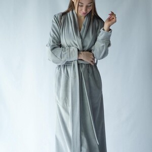 Pu&ograve; includere: Un lungo accappatoio grigio chiaro con collo a scialle e cintura abbinata. L'accappatoio &egrave; realizzato in un materiale morbido e felpato e ha maniche lunghe. L'accappatoio &egrave; progettato per il comfort e il relax.