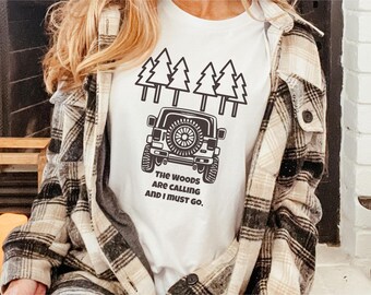 May include: White t-shirt with a black graphic of a jeep driving through a forest. The text "The woods are calling and I must go." is printed below the jeep.
