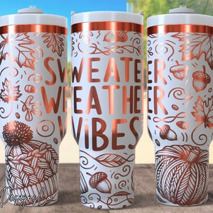 Könnte beinhalten: Weißer isolierter Becher mit kupferfarbenem Design mit Herbstblättern, Eicheln und einer Strickmütze. Die Worte "SWEATER WEATHER VIBES" sind in Kupfer gehalten. Der Becher hat einen weißen Griff und Deckel.
