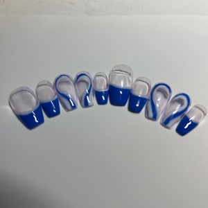 May include: A set of ten false nails with a white and blue swirl design. The nails are clear with a blue tip and a white swirl design.