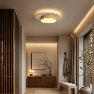 Puede incluir: Una moderna lámpara de techo con diseño circular. Tiene una base de madera, un anillo con efecto hormigón y una luz empotrada brillante. La lámpara está en un pasillo de tonos neutros con detalles de madera y un banco.