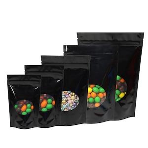 May include: Set of five black stand-up pouches with clear viewing windows. The pouches are various sizes and feature a zipper closure. Each pouch is filled with colourful candy.