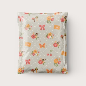 May include: A plastic mailing envelope with a light gray background and a repeating pattern of flowers, cherries, mushrooms, butterflies, and envelopes with hearts.