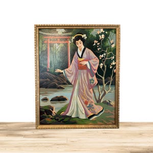 May include: A framed painting of a woman in a pink and purple kimono standing in a Japanese garden. The woman is holding a small yellow bird in her hand. The garden features a red torii gate, a small stream, and a flowering tree.