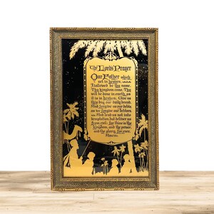 May include: A framed artwork featuring a gold-colored silhouette of a religious scene against a black background. The text "The Lord's Prayer" is displayed in gold lettering. The frame is ornate with a gold finish, adding to the piece's vintage aesthetic.