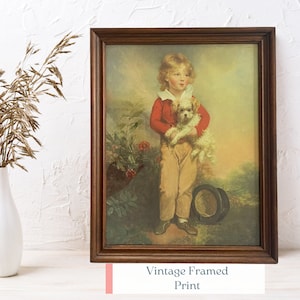 May include: A vintage framed print of a young boy in a red sweater holding a small white dog. The print is set against a backdrop of a lush green garden with red flowers.