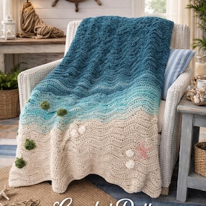 May include: A handmade crochet blanket in shades of blue, turquoise, and beige, resembling a beach scene. The blanket features wave-like patterns, with decorative elements like green pom-poms and a pink starfish. The text "Crochet Pattern House" is visible.