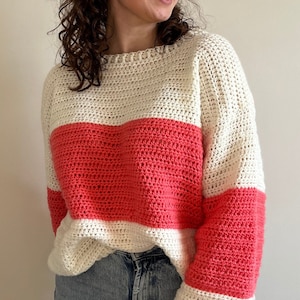 Op de afbeelding: Een witte en koraal gestreepte gehaakte trui met een ontspannen pasvorm. De trui heeft een ronde hals en lange mouwen.