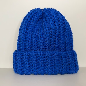 Op de afbeelding: Een felblauwe beanie-muts met een omgeslagen rand. De muts is gemaakt van een dik, getextureerd gebreid materiaal. Deze wintermuts is een stijlvol accessoire voor koud weer.