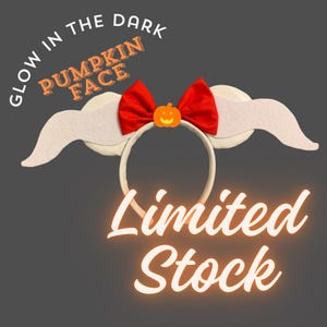 May include: A headband featuring a red bow, a small orange pumpkin icon, and two white wing-like attachments. The text GLOW IN THE DARK PUMPKIN FACE and Limited Stock are visible. The headband has a circular frame and is designed for head wear.