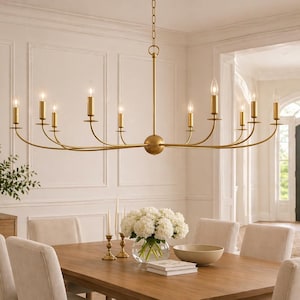 May include: A linear chandelier with a gold finish featuring ten upward-facing candle-style lights arranged on curved arms extending from a central spherical hub, suspended by a chain from a ceiling canopy in a dining room setting.