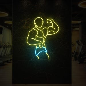 May include: A neon sign showing a muscular figure flexing a bicep. The outline of the bodybuilder is in yellow, with blue shorts. The sign is mounted on a dark, textured wall, suggesting a gym or fitness centre setting.