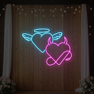 May include: A neon sign depicting two hearts: a blue heart with angel wings and a halo, and a pink heart with devil horns and a tail. The sign is on a wooden wall, with fairy lights and white drapes.
