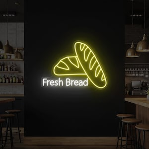 May include: A neon sign with two yellow bread loaves and the words "Fresh Bread" in white. The sign is mounted on a black wall, with a bar and stools in the foreground.