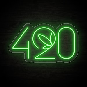 May include: A bright green neon sign displaying the number 420, where the zero is replaced by a stylised circular leaf graphic. The sign features a clear acrylic backing that follows the contour of the numbers, emitting a vibrant glow.