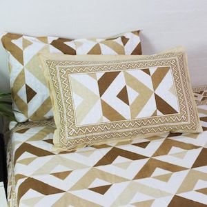 Op de afbeelding: Een beddengoedset met een geometrisch patroon in beige, wit en bruin. De set bevat twee kussenslopen en een hoeslaken. De kussenslopen hebben een rechthoekig ontwerp met een zigzagrand. De beddengoedset is gemaakt van een zacht, comfortabel materiaal.