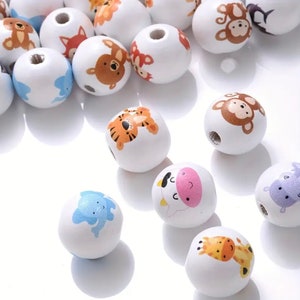 May include: White wooden beads with various animal designs, including a tiger, monkey, elephant, cow, giraffe, and hippopotamus. The beads are approximately 2.5 cm in diameter.
