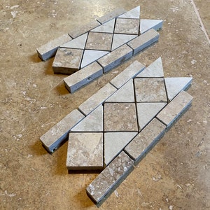 May include: Two pieces of beige and white tile border trim with a diamond pattern. The trim is made of small, irregular shaped tiles.