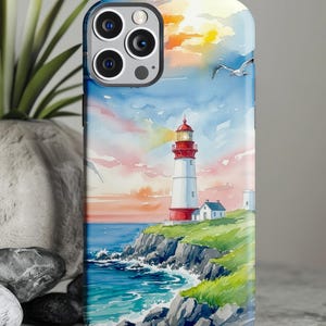 May include: A phone case featuring a watercolor painting of a lighthouse on a cliffside. The lighthouse is white with a red top, set against a blue ocean and a colorful sunset sky. Seagulls fly overhead.