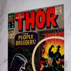 Puede incluir: Portada de cómic vintage de "The Mighty Thor" número 134. La portada presenta a Thor en acción contra figuras verdes, con una combinación de colores rojo y azul. El título es "The People Breeders!" e incluye el logotipo de Marvel Comics Group. Con Quicksilver y La Bruja Escarlata.